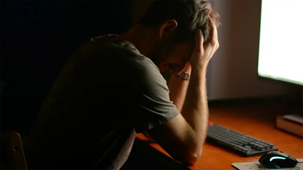 A man crying sitting at his computer.